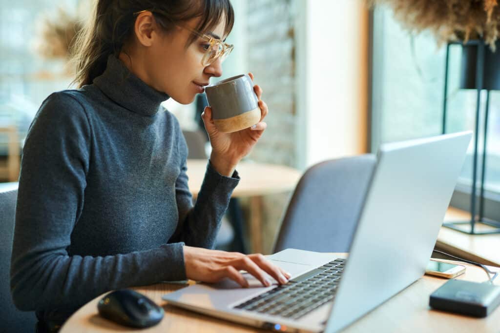 Young woman enjoying coffee during work on laptop